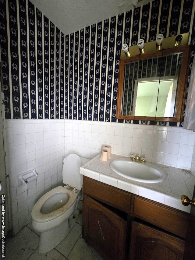 bathroom featuring tile walls, toilet, and vanity