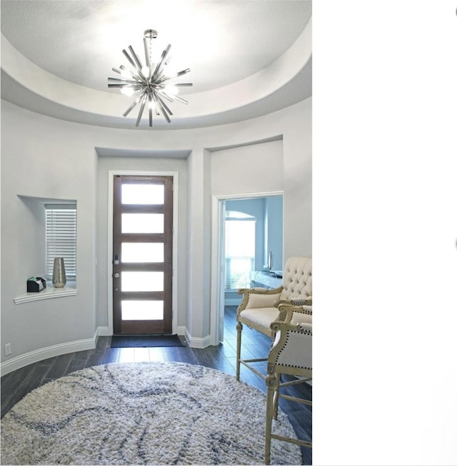 foyer entrance with a raised ceiling and an inviting chandelier