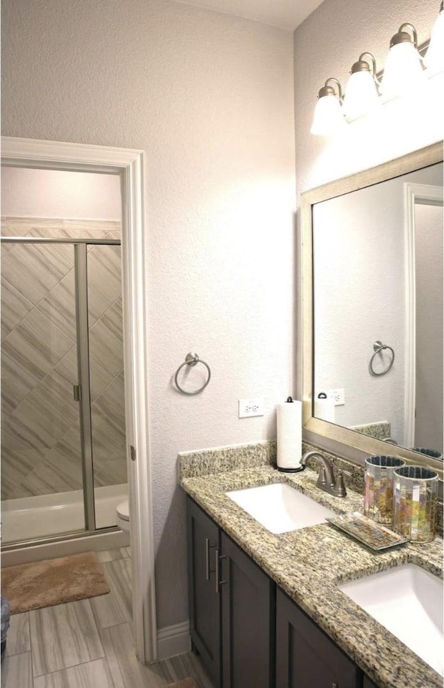 bathroom with toilet, vanity, and an enclosed shower