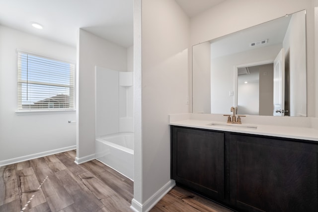 bathroom featuring hardwood / wood-style flooring, vanity, and bathing tub / shower combination