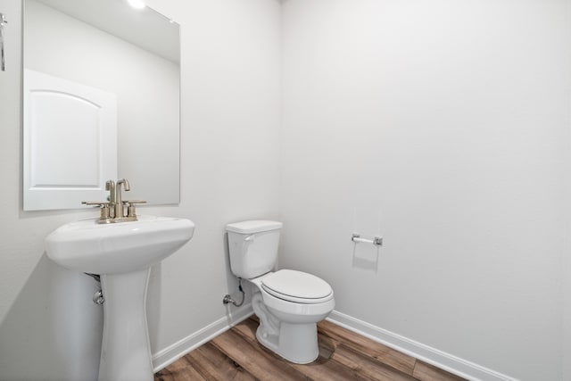 bathroom with toilet, wood-type flooring, and sink