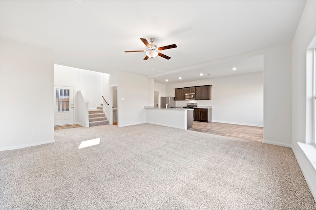 unfurnished living room with ceiling fan and light carpet