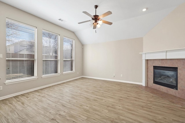 unfurnished living room with ceiling fan, light wood-type flooring, a tile fireplace, and vaulted ceiling