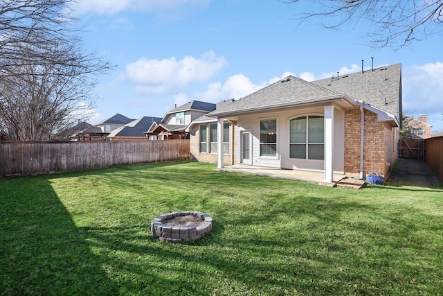 rear view of house with an outdoor fire pit, a lawn, and a patio