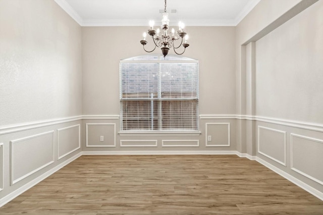 unfurnished dining area with wood-type flooring, crown molding, and a chandelier