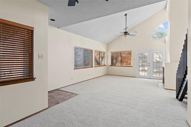 unfurnished living room with lofted ceiling, french doors, carpet floors, and ceiling fan