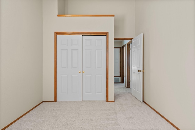 unfurnished bedroom featuring light carpet and a closet