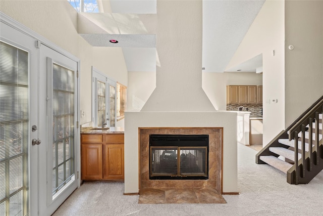 unfurnished living room with light carpet, a tiled fireplace, and vaulted ceiling