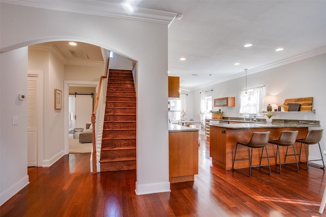 kitchen with kitchen peninsula, dark wood-type flooring, and ornamental molding