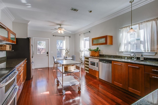 kitchen featuring decorative light fixtures, appliances with stainless steel finishes, sink, and ornamental molding