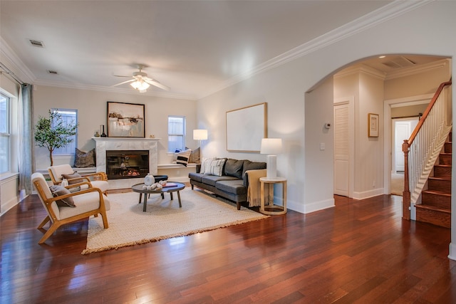 living room featuring ceiling fan, ornamental molding, a fireplace, and plenty of natural light