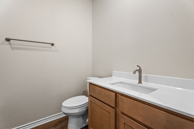 bathroom with toilet, vanity, and wood-type flooring