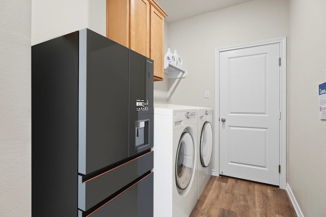 clothes washing area with cabinets, washer and clothes dryer, and dark hardwood / wood-style floors