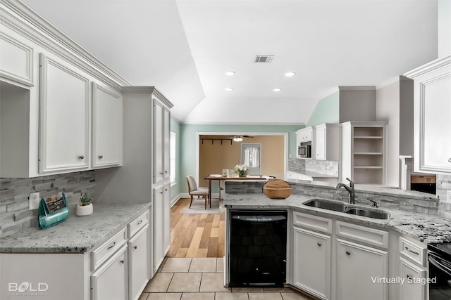 kitchen featuring black dishwasher, sink, white cabinets, and decorative backsplash