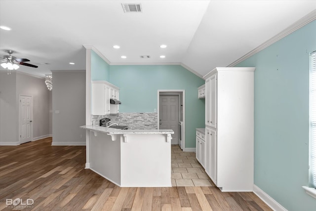 kitchen featuring sink, white cabinetry, a kitchen breakfast bar, kitchen peninsula, and light stone countertops