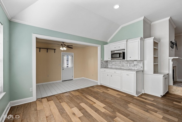 kitchen featuring lofted ceiling, ornamental molding, and white cabinets