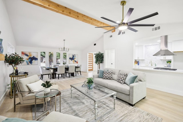 living room featuring beam ceiling, sink, light hardwood / wood-style flooring, high vaulted ceiling, and ceiling fan with notable chandelier