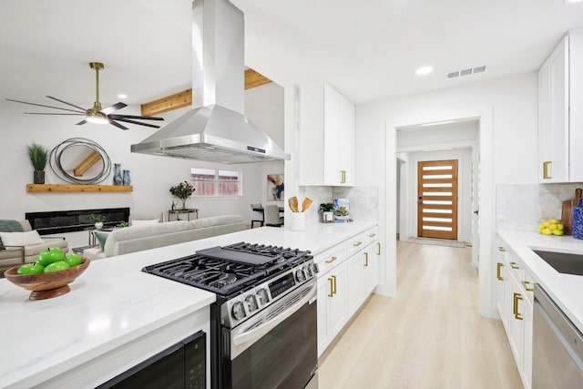 kitchen featuring decorative backsplash, appliances with stainless steel finishes, island exhaust hood, and white cabinetry