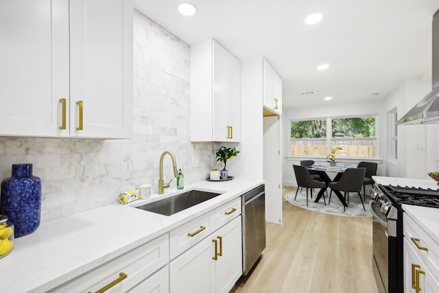 kitchen featuring white cabinetry, gas range oven, stainless steel dishwasher, and sink