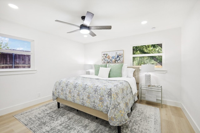 bedroom featuring light wood-type flooring, ceiling fan, and multiple windows