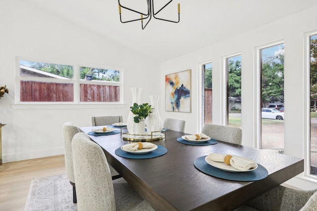 dining area featuring lofted ceiling, a chandelier, and light wood-type flooring