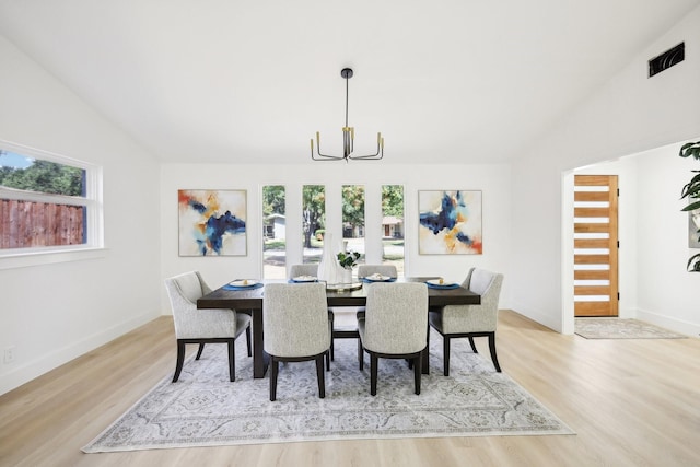 dining room with vaulted ceiling, an inviting chandelier, and light hardwood / wood-style floors