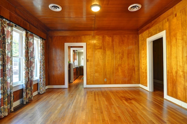 empty room featuring wooden ceiling, light hardwood / wood-style flooring, and wooden walls