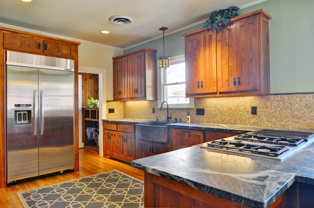 kitchen featuring decorative light fixtures, stainless steel appliances, sink, light wood-type flooring, and crown molding