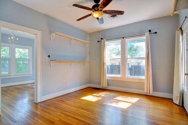 unfurnished room featuring light wood-type flooring and ceiling fan with notable chandelier