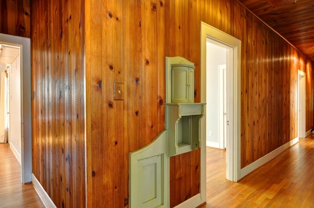 corridor with wood walls, wood ceiling, and light wood-type flooring