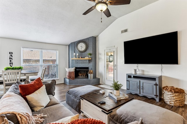 living room featuring ceiling fan, vaulted ceiling, a fireplace, a textured ceiling, and dark hardwood / wood-style flooring