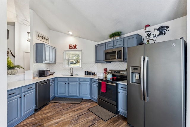 kitchen with stainless steel appliances, dark hardwood / wood-style floors, blue cabinets, vaulted ceiling, and sink