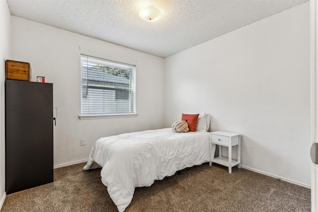 bedroom with a textured ceiling and dark colored carpet