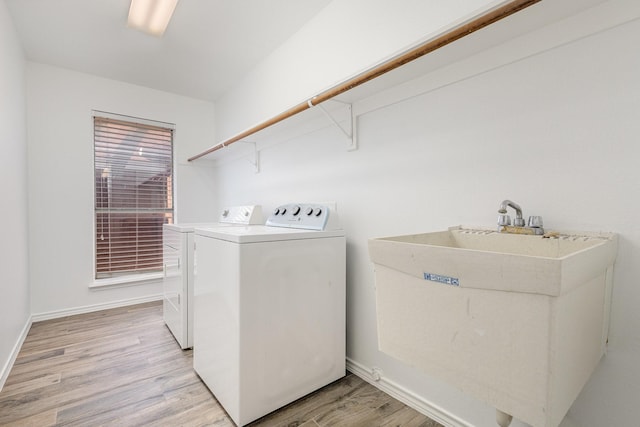 washroom featuring sink, washing machine and clothes dryer, and light hardwood / wood-style floors