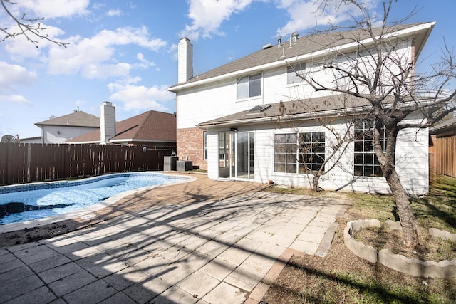 rear view of house featuring a patio area, a fenced in pool, and central air condition unit