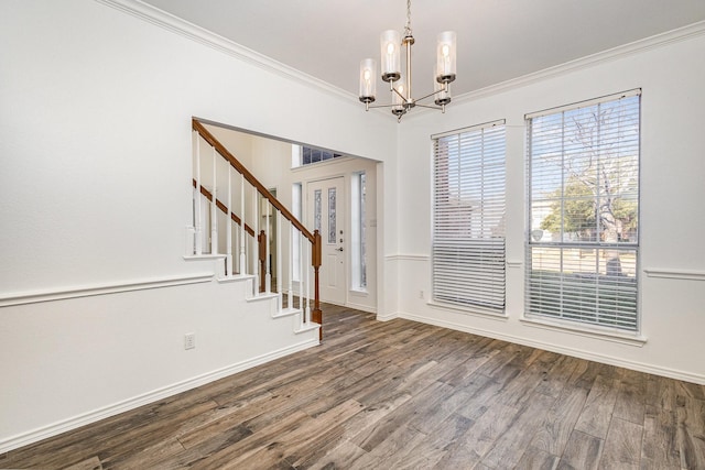 spare room with ornamental molding, wood-type flooring, and a notable chandelier