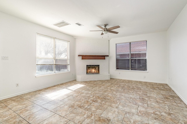 unfurnished living room with a brick fireplace and ceiling fan