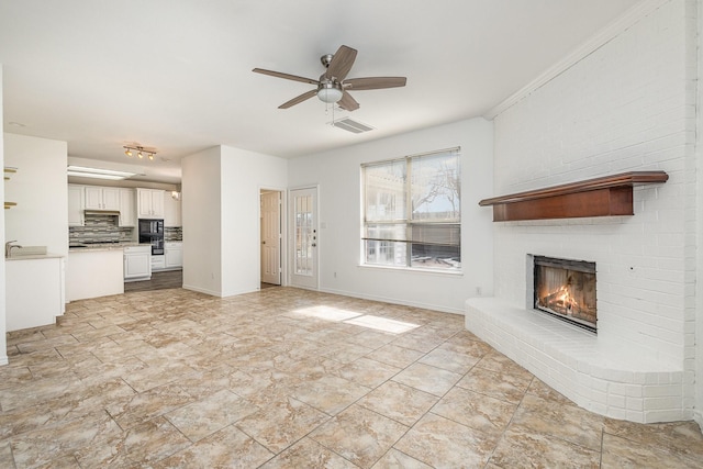 unfurnished living room with a brick fireplace and ceiling fan