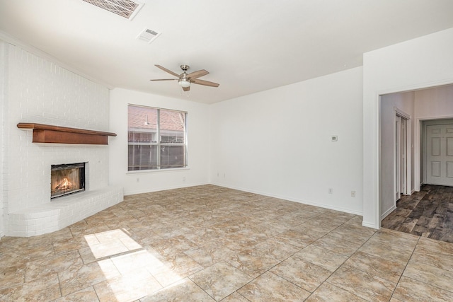 unfurnished living room featuring ceiling fan and a brick fireplace