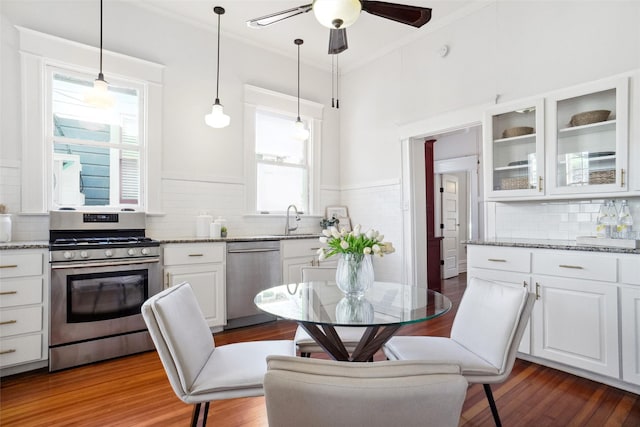 kitchen featuring pendant lighting, sink, white cabinets, light stone counters, and stainless steel appliances