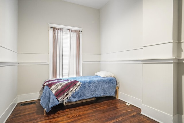 bedroom with multiple windows and dark hardwood / wood-style flooring