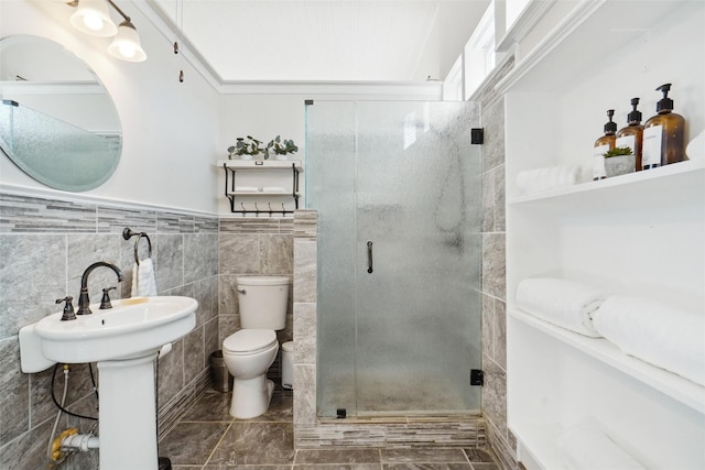 bathroom with tile walls, sink, a shower with shower door, and toilet