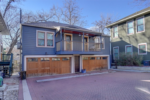 view of front of house with a garage, a balcony, and cooling unit