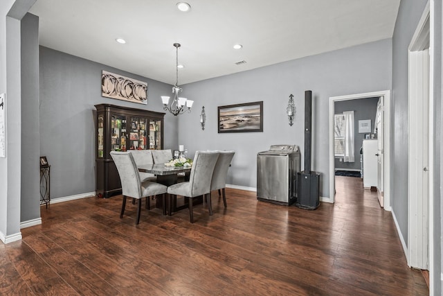 dining room with dark hardwood / wood-style flooring, washer / clothes dryer, and a notable chandelier