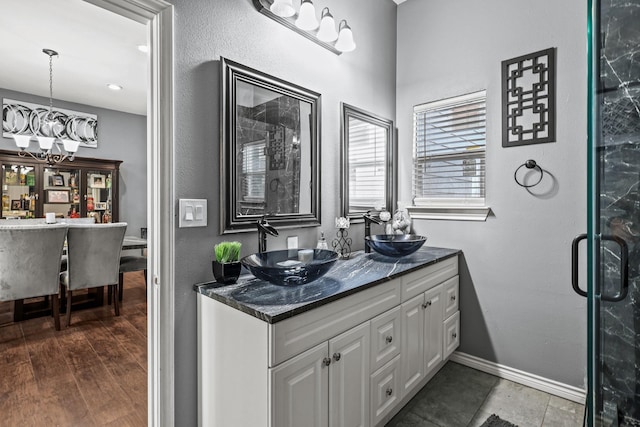 bathroom with tile patterned flooring, an enclosed shower, vanity, and an inviting chandelier