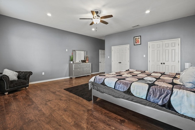 bedroom featuring ceiling fan, dark wood-type flooring, and two closets