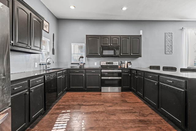 kitchen featuring black appliances, kitchen peninsula, dark wood-type flooring, and sink