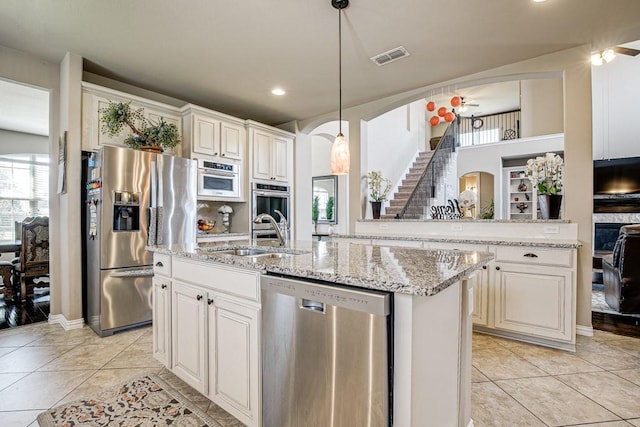 kitchen featuring pendant lighting, a center island with sink, sink, white cabinetry, and appliances with stainless steel finishes