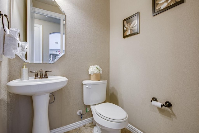 bathroom with toilet, tile patterned flooring, and sink