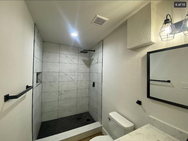 bathroom with toilet and a tile shower